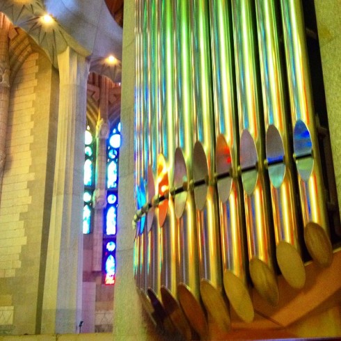 Organ pipes coloured by the afternoon sunlight through the enormous stained glass windows.